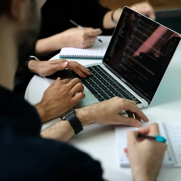 Hands working on code and handwritten notes