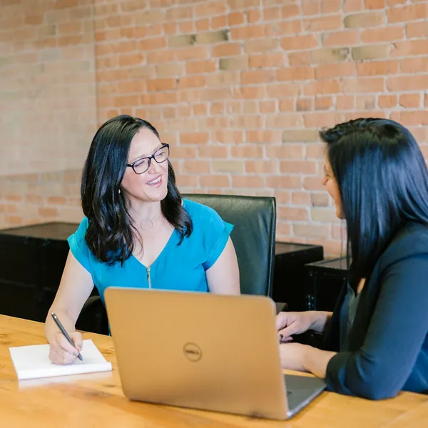 Two people talking across a table with a laptop open
