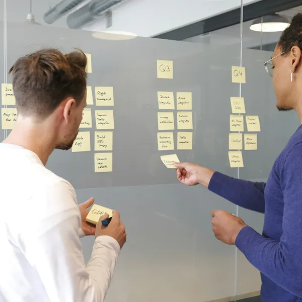 Two colleagues planning with sticky notes on a glass wall