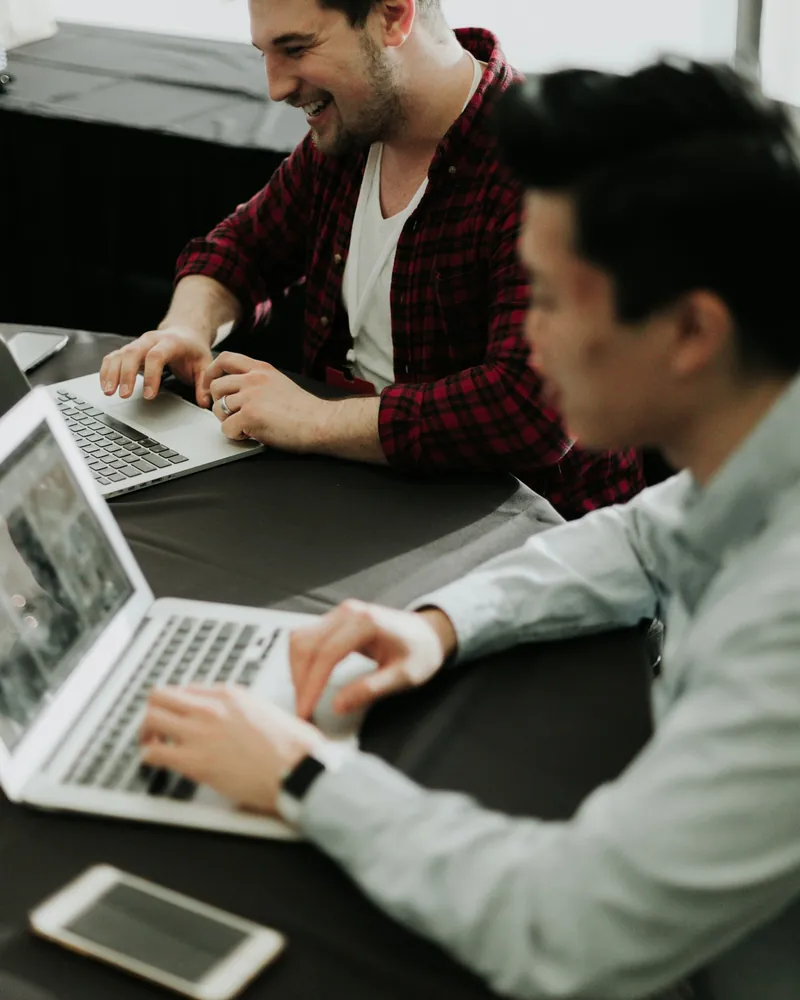 Two colleagues working through a plan together on laptops