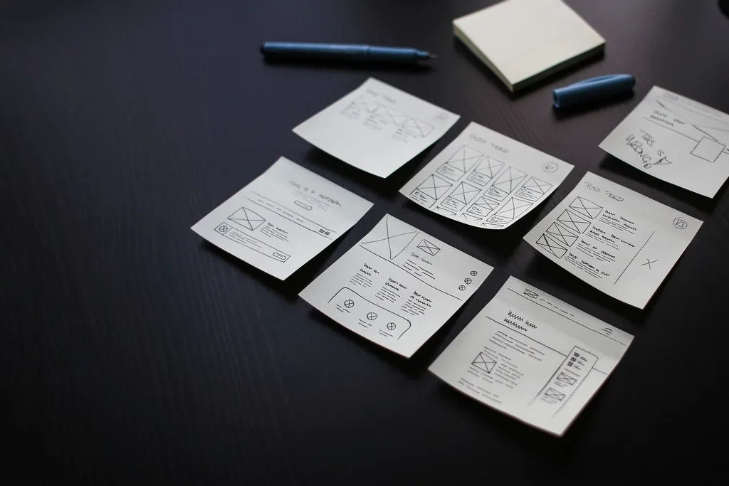 Wireframe sketches on sticky notes spread across a desk